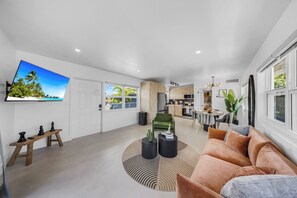 A modern living room with a sofa, coffee table, and a TV mounted on the wall. - Boutique Stay - Resort -5min to beach-near shop (Fort Lauderdale)