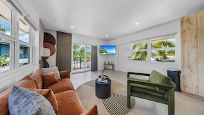 Un salon moderne avec un canapé, un fauteuil vert, une table basse et un téléviseur.