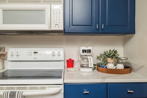 A kitchenette with a microwave, stove, coffee maker, and blue cabinets. - New! Starkville Retreat | Walk to MSU (Starkville)