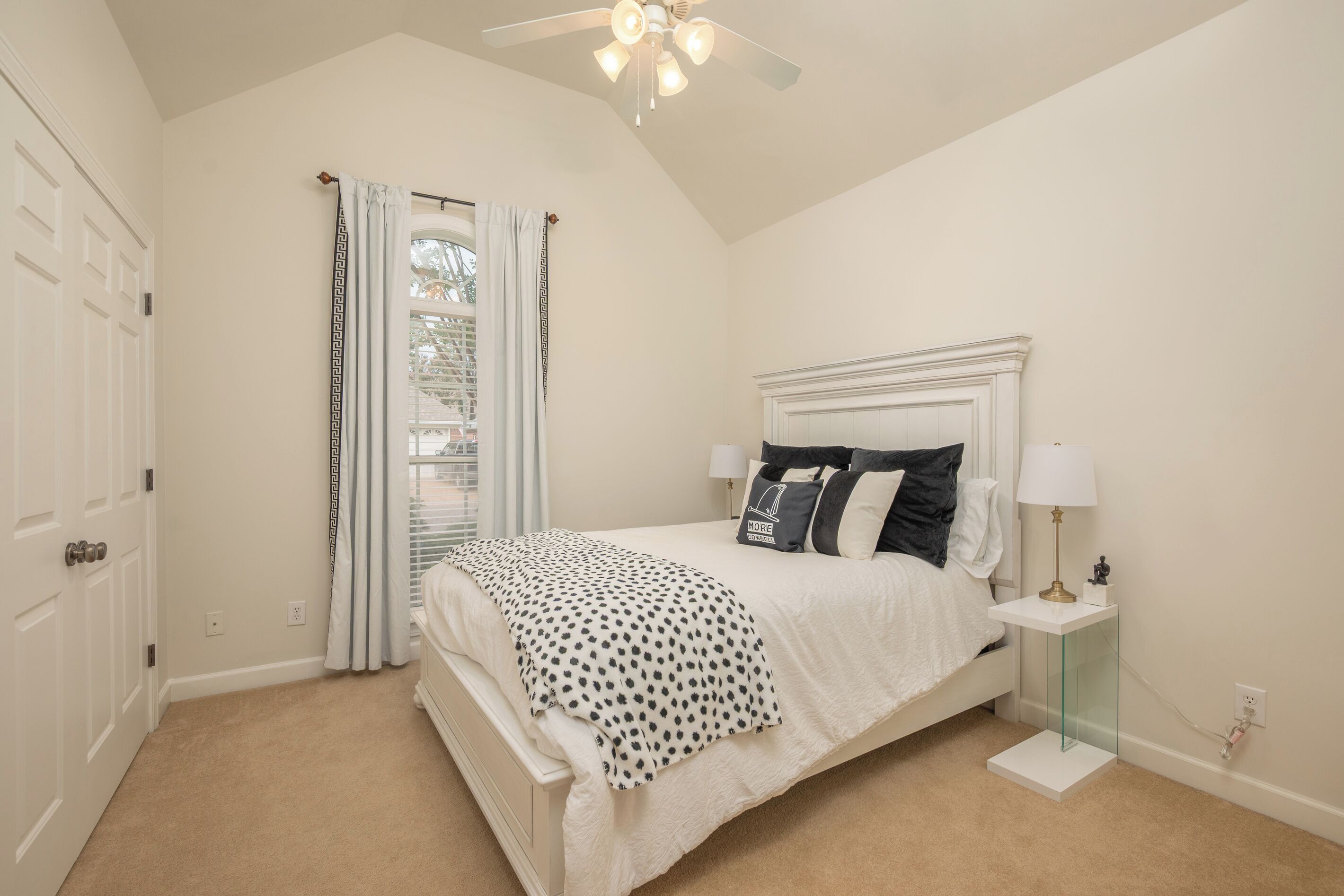 A bedroom with a bed, a nightstand, a lamp, and a ceiling fan.