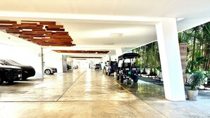 Un parcheggio coperto moderno con pavimento bagnato, un golf cart e diverse automobili.