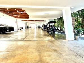 A modern indoor parking garage with a wet floor, a golf cart, and several cars. - Oceanfront Corner Unit  Full Ocean View  Beachfront Pool Parking  Jaco (Jaco)