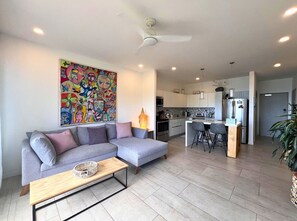 Un salon moderne avec un canapé gris, une table basse et un tableau abstrait aux couleurs vives accroché au mur.