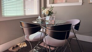 Una habitación con una mesa de vidrio redonda, cuatro sillas, un jarrón con flores y un letrero de 'No Fumar'.
