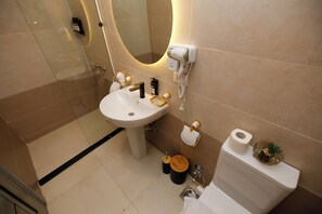Un baño con lavamanos, espejo, inodoro y secador de pelo en la pared.