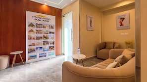 Un vestíbulo de hotel con una recepción, un área de estar con dos sofás, una mesita con una botella de agua y un cartel informativo grande sobre las Pirámides de Giza.