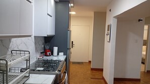 Eine moderne Küche mit weißen Schränken, einem Gasherd, einem roten Mixer und einer Marmor-Spritzschutzwand.