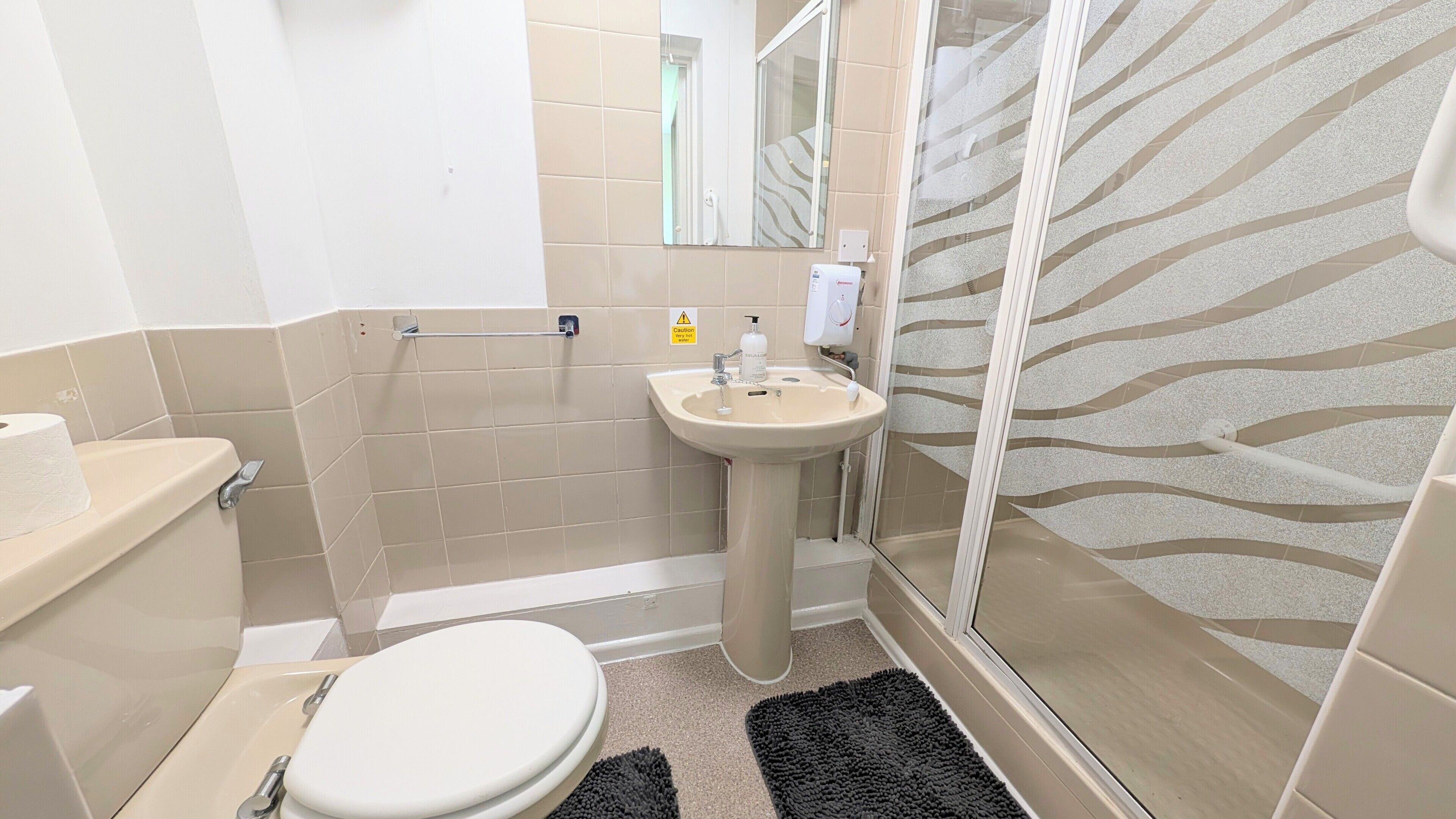 A bathroom with a toilet, sink, and shower.