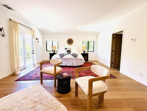 A bedroom with a bed, two chairs, a rug, and a small table with a book.