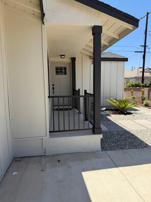 A residential building with a covered porch, a gated entrance, and a small garden area. - 4-bedroom bungalow in welcoming Gardena with AC comfort (Gardena)