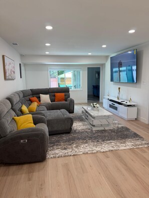 Un salon moderne avec un canapé d’angle, un téléviseur à écran plat et une table basse.