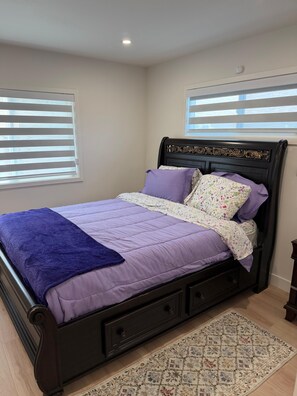 Ein Bett mit Kopfteil, einer violetten Decke und einem Kissen mit Blumenmuster.