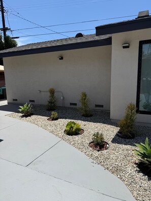 A modern building with a flat roof, a small window, and a concrete pathway leading to the entrance. - 4-bedroom bungalow in welcoming Gardena with AC comfort (Gardena)
