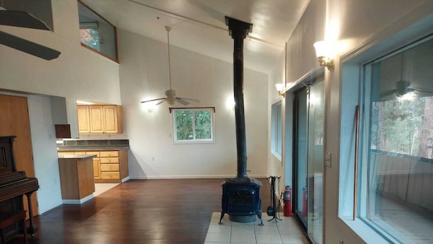 Amplia sala de estar con chimenea, piso de madera y vistas a través de amplios ventanales.