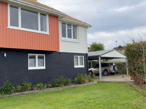 A two-story house with a red and black exterior, a covered carport, and a well-maintained lawn. - Tyne above Town - Convenient. Comfortable. Clean. (Oamaru)