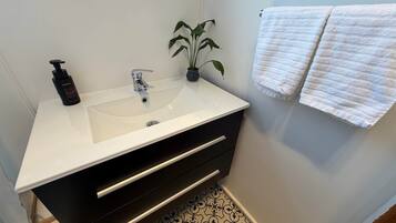 A bathroom with a white sink, black cabinet, and a potted plant.