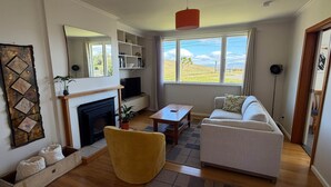 A living room with a fireplace, sofa, coffee table, and a view of the outdoors.