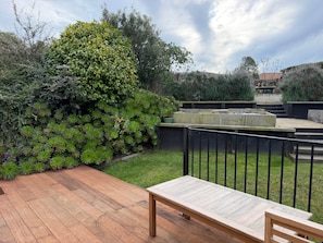 A wooden deck with a bench, surrounded by lush greenery and a stone wall. - Tyne above Town - Convenient. Comfortable. Clean. (Oamaru)