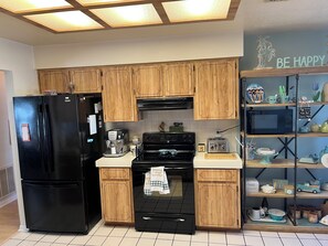 A kitchen with wooden cabinets, a black refrigerator, a coffee maker, a toaster, and a microwave. - Beautiful 2-bedroom house with in convenient Spring Hill (Spring Hill)