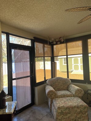 A room with a sliding glass door, a floral-patterned sofa, and a small table with a lamp. - Beautiful 2-bedroom house with in convenient Spring Hill (Spring Hill)