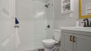 Een badkamer met een wit toilet, een douche en een wastafel met een goudkleurige kraan.