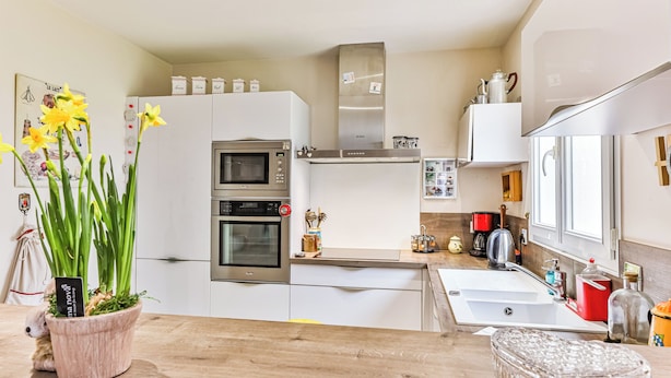 A modern kitchen with white cabinets, a Bosch oven, a sink, and a window.