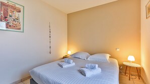 A hotel room with a bed, two bedside lamps, a wall decoration, and a bedside table.