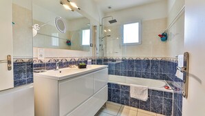 A modern bathroom with a glass shower enclosure, a white vanity, and a bathtub.