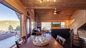Un interior de madera con una mesa de comedor, sillas, una chimenea y vistas al exterior.