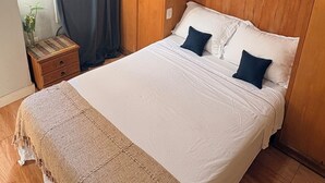 A bedroom with a bed, wooden wardrobe, and a nightstand. - Suite in a shared apartment in Glória, Rio de Janeiro. (Rio de Janeiro)