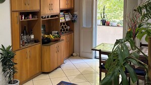 A kitchen with wooden cabinets, a dining table, and potted plants. - Suite in a shared apartment in Glória, Rio de Janeiro. (Rio de Janeiro)