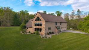 A two-story house with a stone facade, a large front yard, and a driveway leading to a garage. - Mountaintop Cabin|Game Room|Pickleball (Elliottsburg)