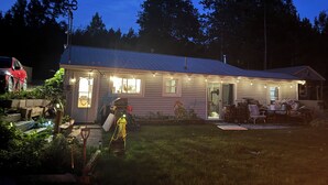 Une maison de plain-pied avec un toit en métal, un porche à l’avant et une petite terrasse.