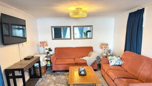 Un salon avec un canapé, une table basse, un téléviseur et des lampes.
