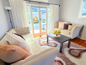 A living room with a sofa, armchairs, a coffee table, and a view through a glass door. - Parnell Gem | Walk to Domain & Hospital (Parnell)