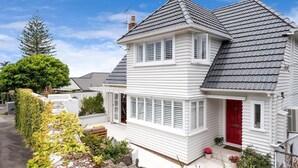 Une maison à deux étages avec une porte rouge, un revêtement extérieur blanc et un toit gris.