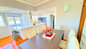 Un coin repas avec une table en bois foncé, des chaises à revêtement blanc et un centre de table floral.