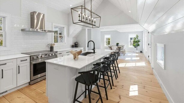 A modern kitchen with white cabinetry, a stainless steel range, and a central island with bar stools. - Capeside: 540-O Vintage Luxury in Orleans (Orleans)