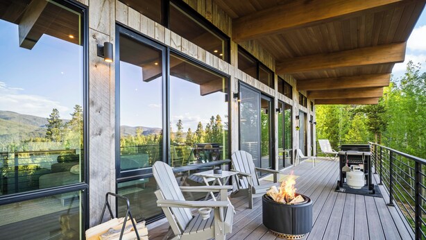 Une terrasse avec des fauteuils Adirondack, un foyer et un barbecue.