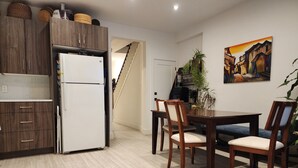 Une cuisine moderne avec des meubles en bois, un réfrigérateur blanc et un coin repas comprenant une table et des chaises en bois.