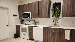 Une cuisine moderne avec des meubles en bois, un micro-ondes blanc, une cuisinière et un lave-vaisselle.