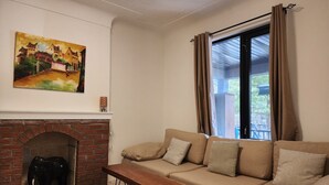 Un salon avec un canapé, une table basse en bois, une cheminée et un tableau accroché au mur.