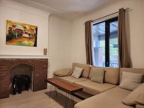 A living room with a sofa, a wooden coffee table, a fireplace, and a painting on the wall.