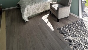 Un dormitorio con una cama, una silla, un ventanal y dos cuadros en la pared.