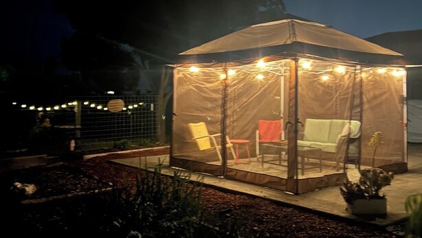 Una carpa con un área de estar cubierta y luces colgantes.