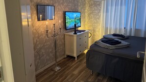 A bedroom with a bed, a nightstand, a TV, a candelabra, and a mirror.