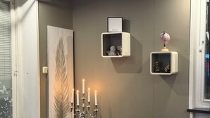 A room with a candelabra, a framed artwork, and two shelves with decorative items.