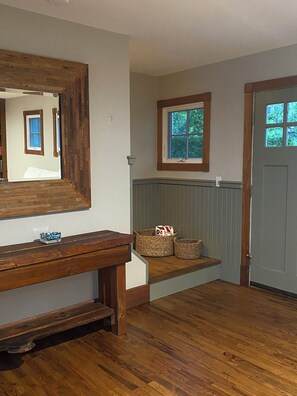 A hallway with a wooden bench, a mirror, a window, and a door. - 4 miles from Shinnecock Hills US Open - on the water newly renovated (Hampton Bays)