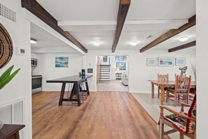 Una cocina amplia con una mesa y sillas de madera, un comedor con mesa y sillas de madera, y una escalera que conduce a un nivel superior.