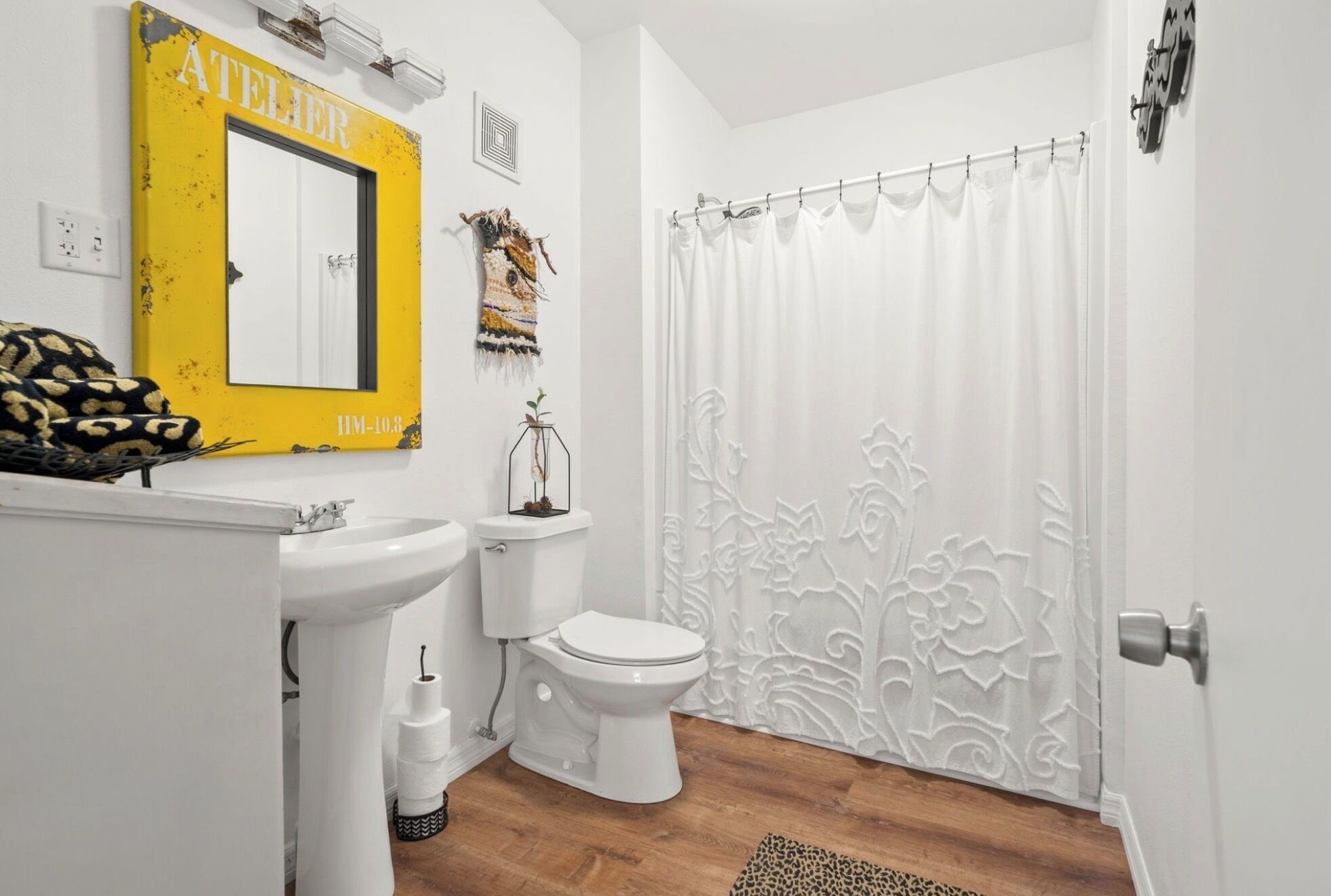A bathroom with a yellow mirror, white toilet, and shower curtain.